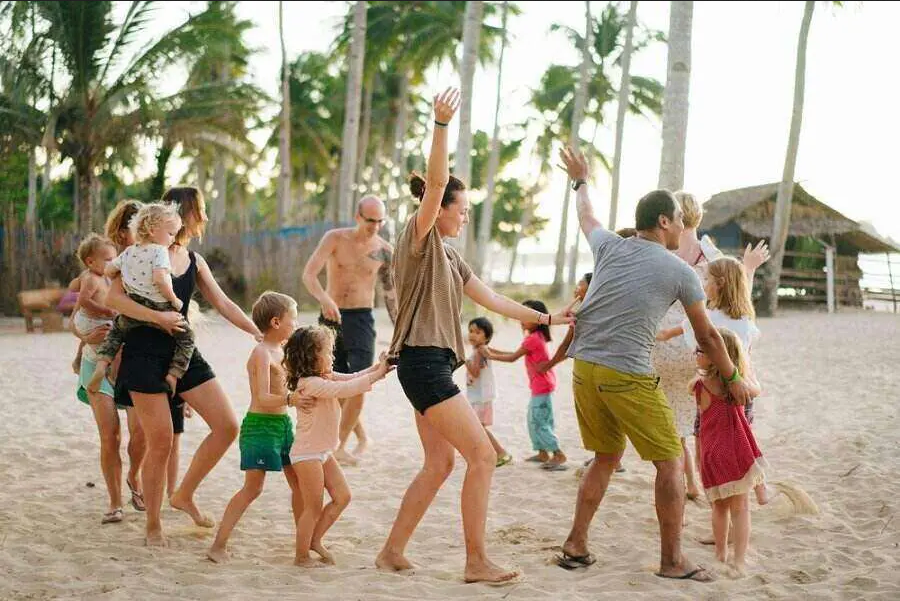 a group of people standing on top of a sandy beach next to palm trees